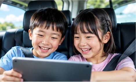 車内でタブレットを見て喜ぶ子どもたち